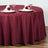 Burgundy tablecloth draped over a round table set for dining.