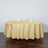 Round gold tablecloth on a dining table with glasses and napkins.