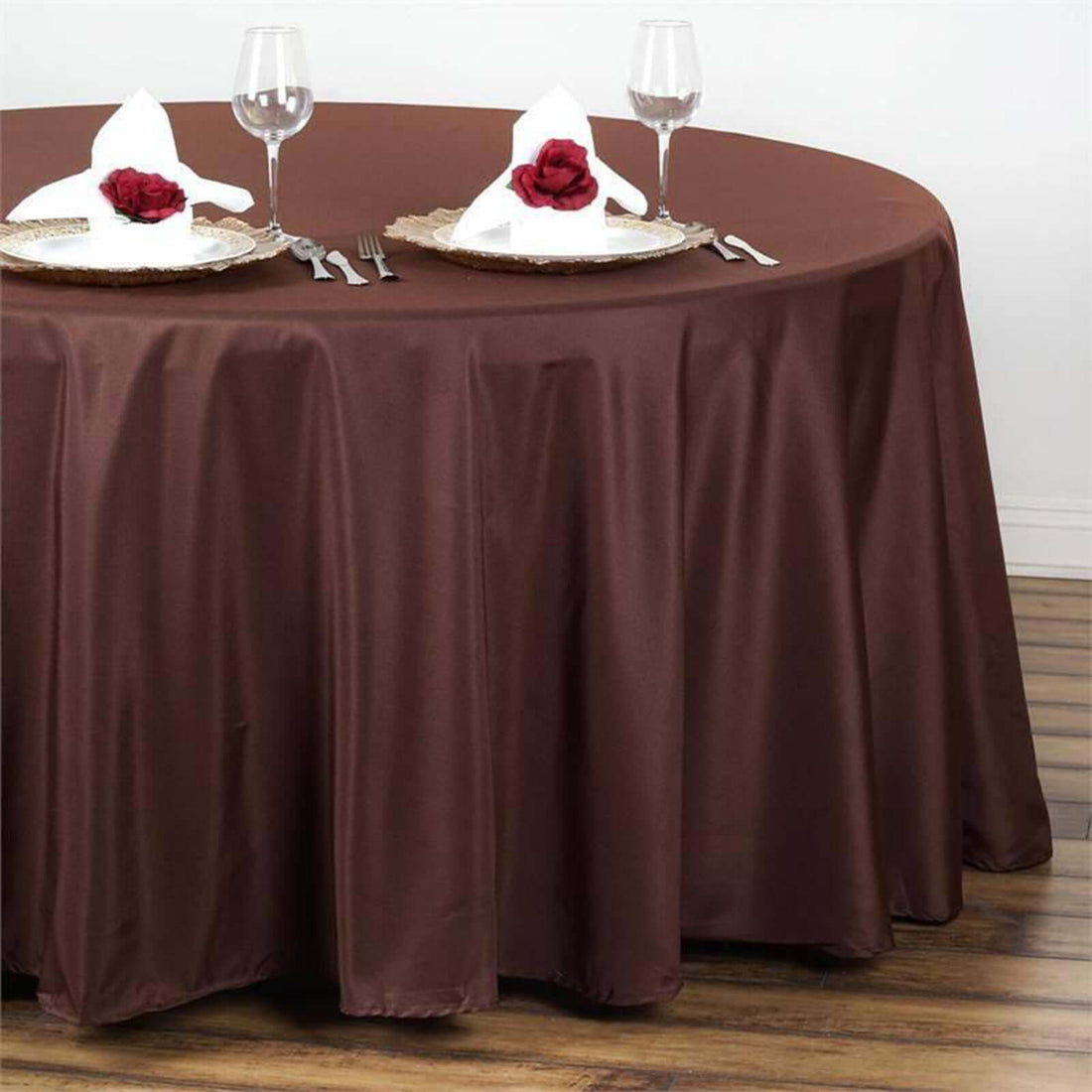 Brown tablecloth draped over a round table set with plates and napkins.