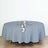 Round gray tablecloth with floral centerpiece and plates set for dining.
