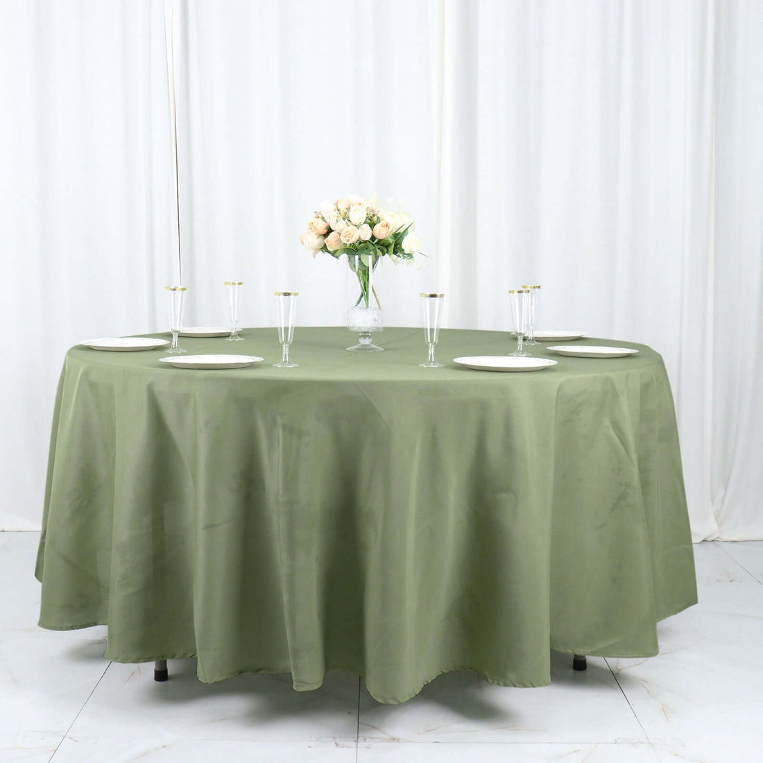 Round olive green tablecloth set for an elegant dining arrangement.