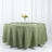 Round olive green tablecloth set for an elegant dining arrangement.