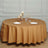 Round brown tablecloth on a dining table set with plates and decorative candles.
