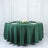 Green round tablecloth draped over a table set for dining.
