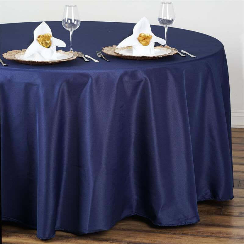 Navy blue tablecloth with elegant napkin folds on a round table setting.