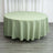Green round tablecloth on a wooden floor with curtains in the background.