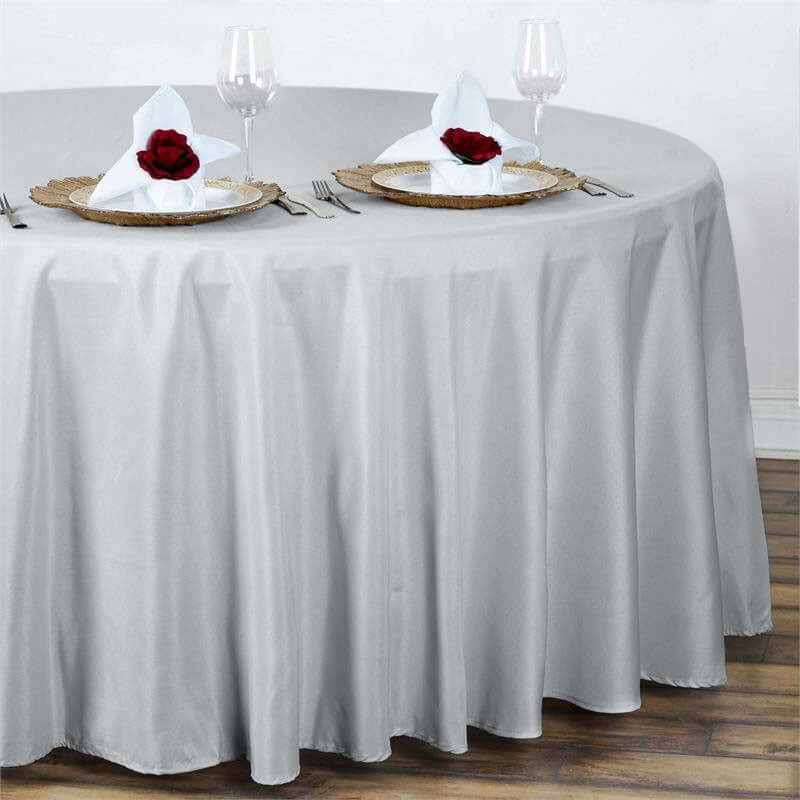 Elegant gray tablecloth draped over a round table with place settings and rose accents.