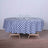 Round blue and white checked tablecloth on a wooden table with glasses.