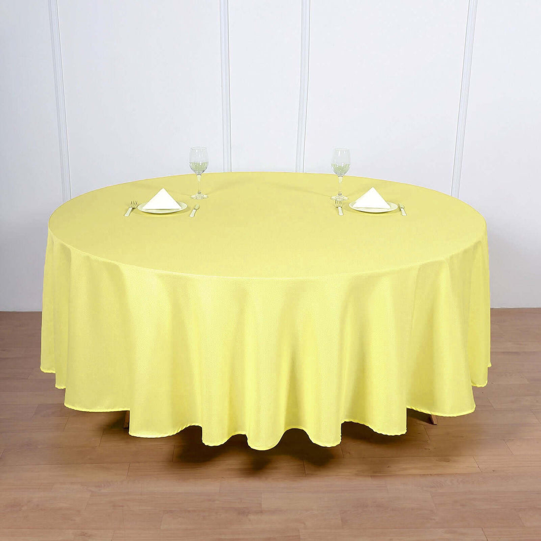 Round yellow tablecloth draped over a table with glasses and napkins