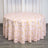 Round pink tablecloth with geometric gold pattern on a wooden surface.