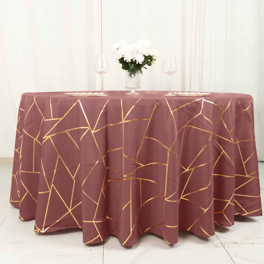 Elegant maroon tablecloth with gold geometric patterns on a round table.
