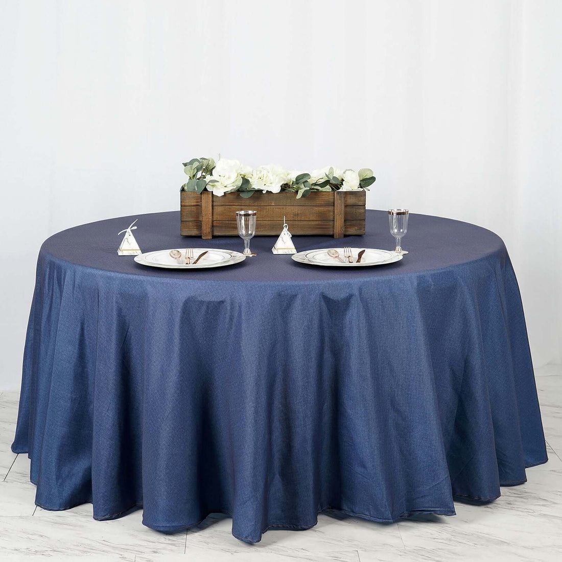 Round navy tablecloth styled with plates and decorative centerpiece.