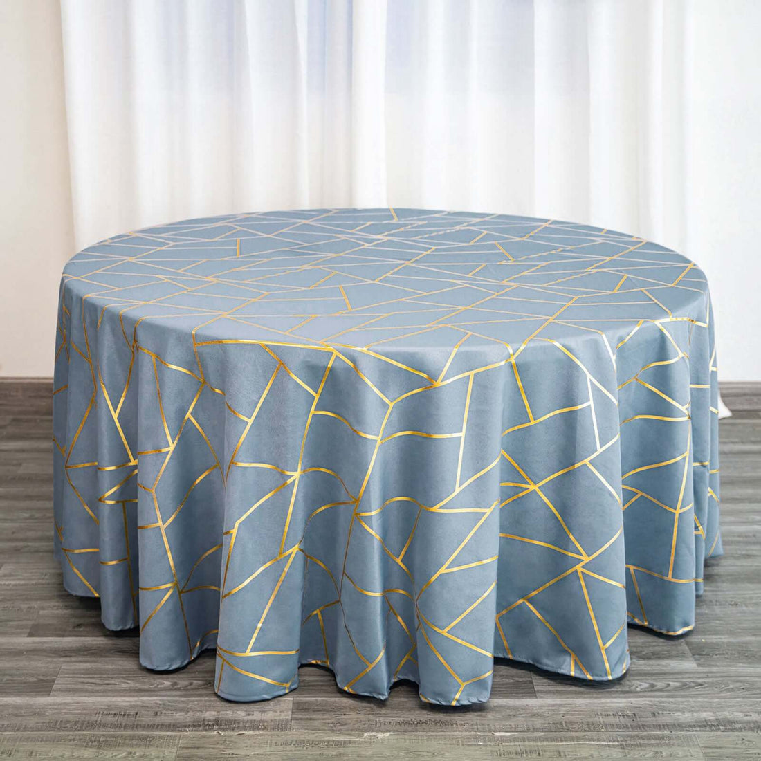 Round blue tablecloth with gold geometric pattern on a wooden table.