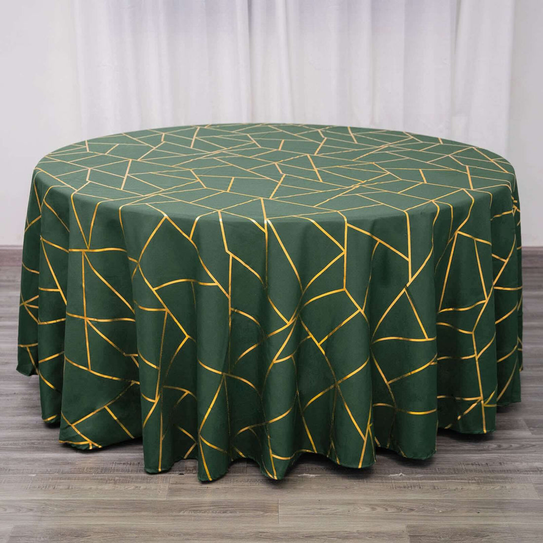 Green geometric patterned round tablecloth on a wooden surface.