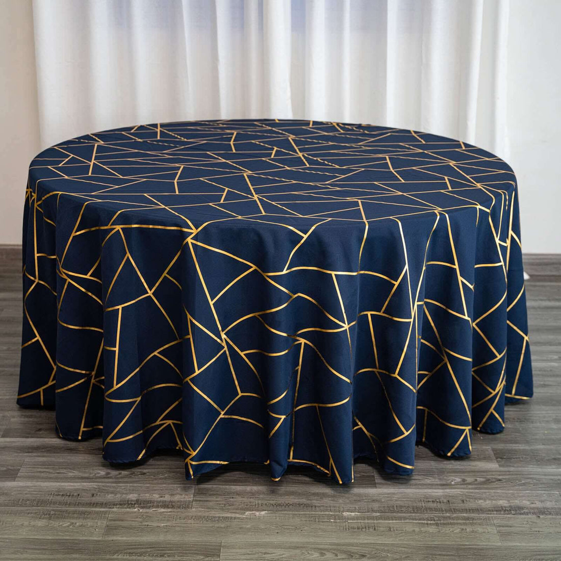 Round navy tablecloth with gold geometric pattern on a wooden surface.