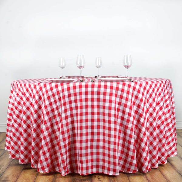 Red and white checkered tablecloth on a round table with wine glasses.
