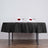 Elegant dining setup with black tablecloth, glasses, and rose-adorned napkins.