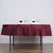 Elegant table setting with maroon tablecloth, white napkins, and rose accents.