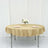 Round gold tablecloth draped over a table set for two with flowers and glasses.