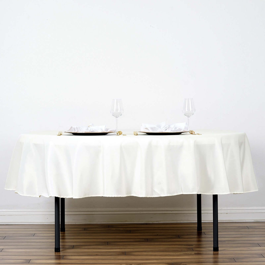 Elegant white tablecloth draped on a table set for two with plates and glasses.
