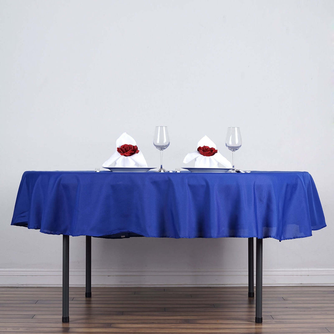 Elegant blue tablecloth with white napkins and roses on a dining table.
