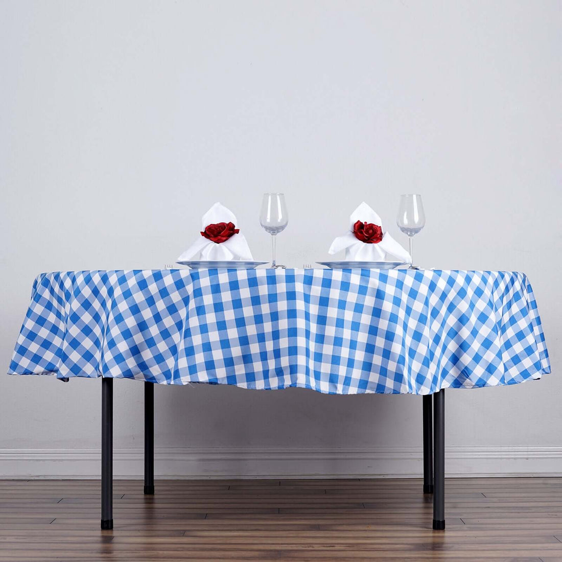 Blue and white checkered tablecloth with rose-adorned napkins and wine glasses.