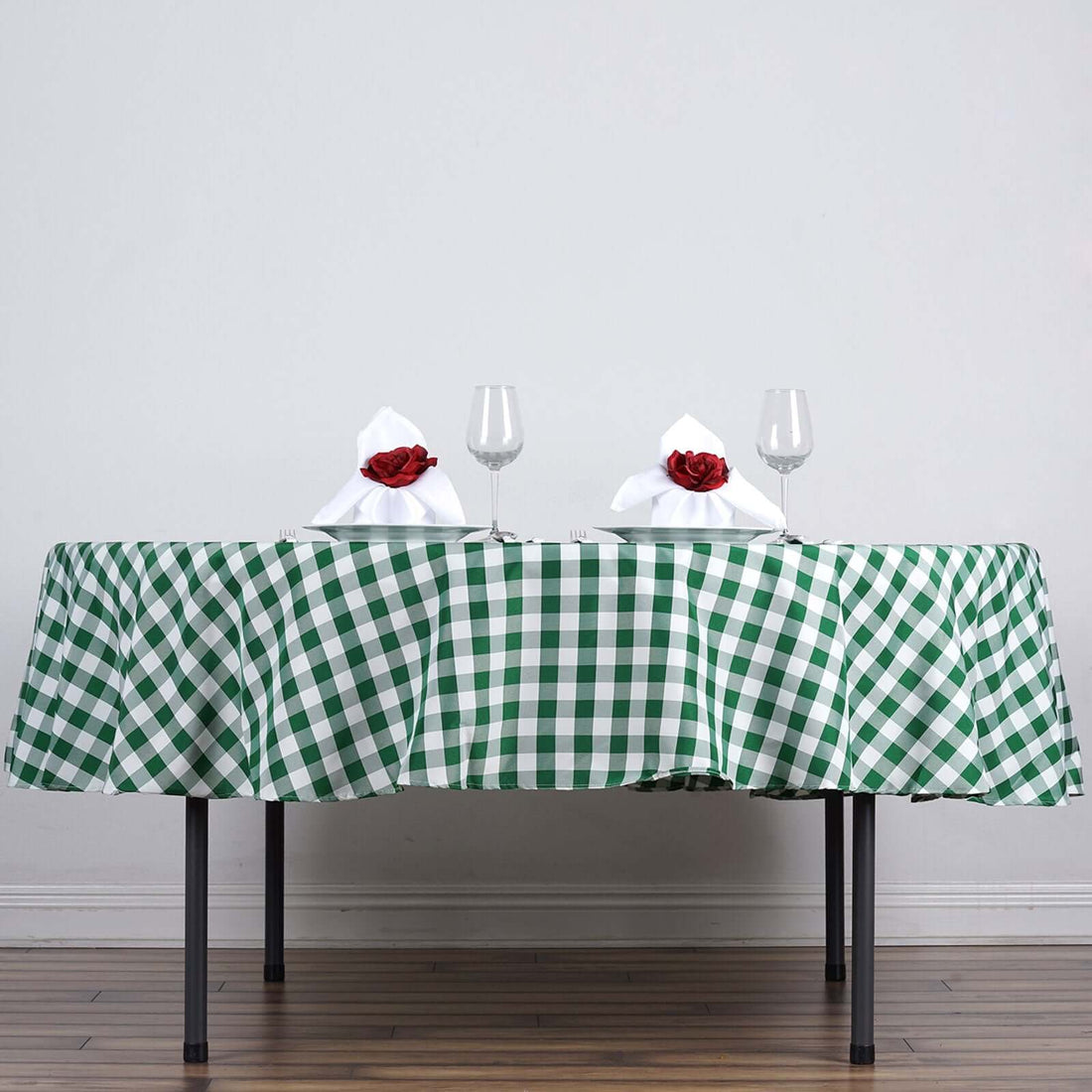 Table set with a green checkered tablecloth, glasses, and napkins with roses.
