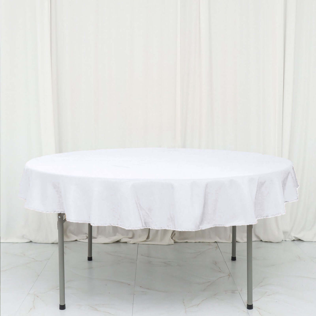 Round white tablecloth draped over a folding table.