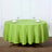 Green round tablecloth on a wooden table with plates and glasses.