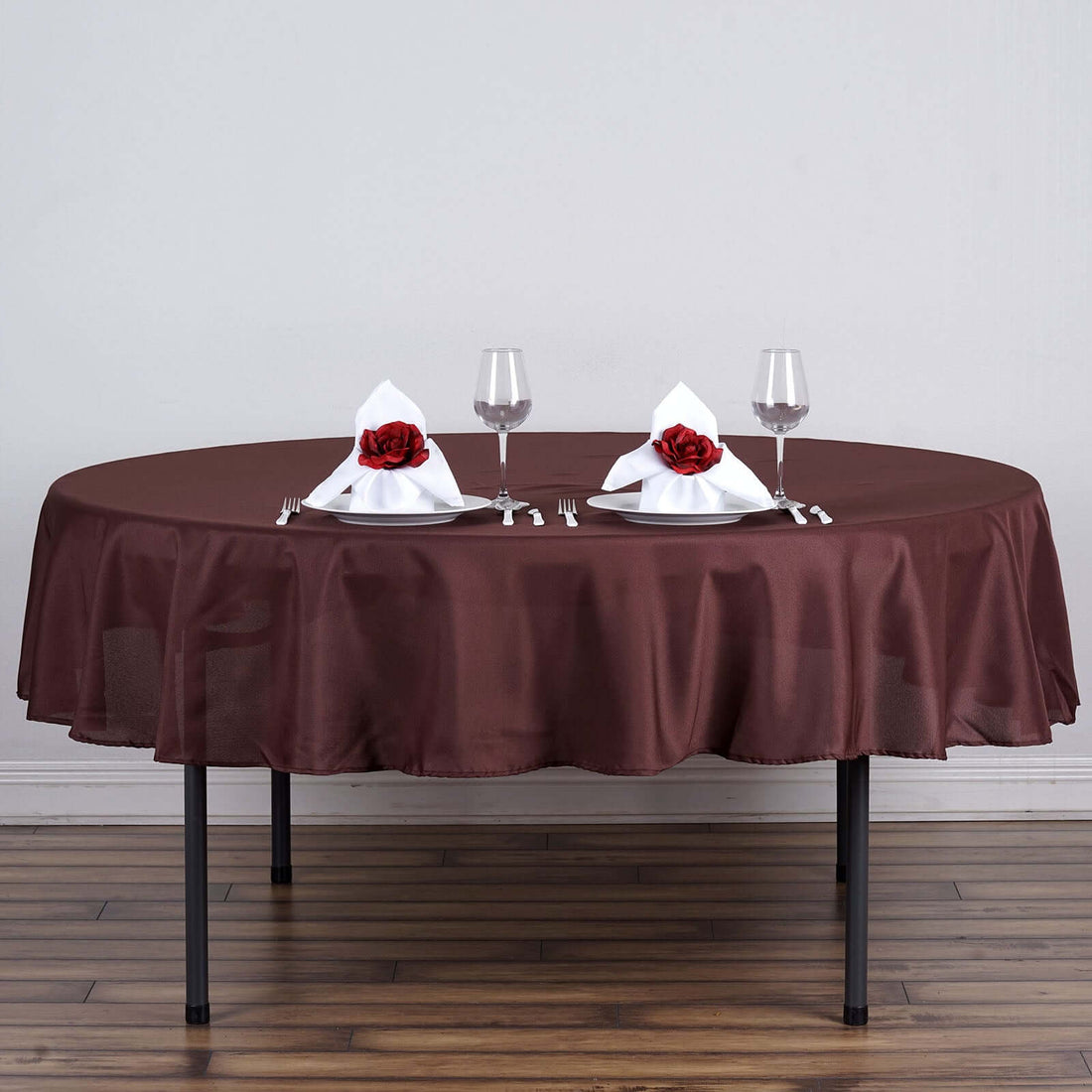 Elegant brown tablecloth with white napkins and red roses set for dining.