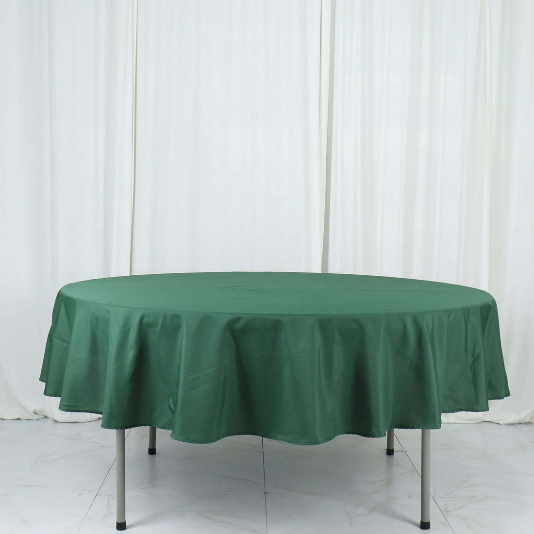 Green round tablecloth draped over a table against a light background.