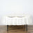 Round white tablecloth draped over a table with elegant dinnerware and glasses