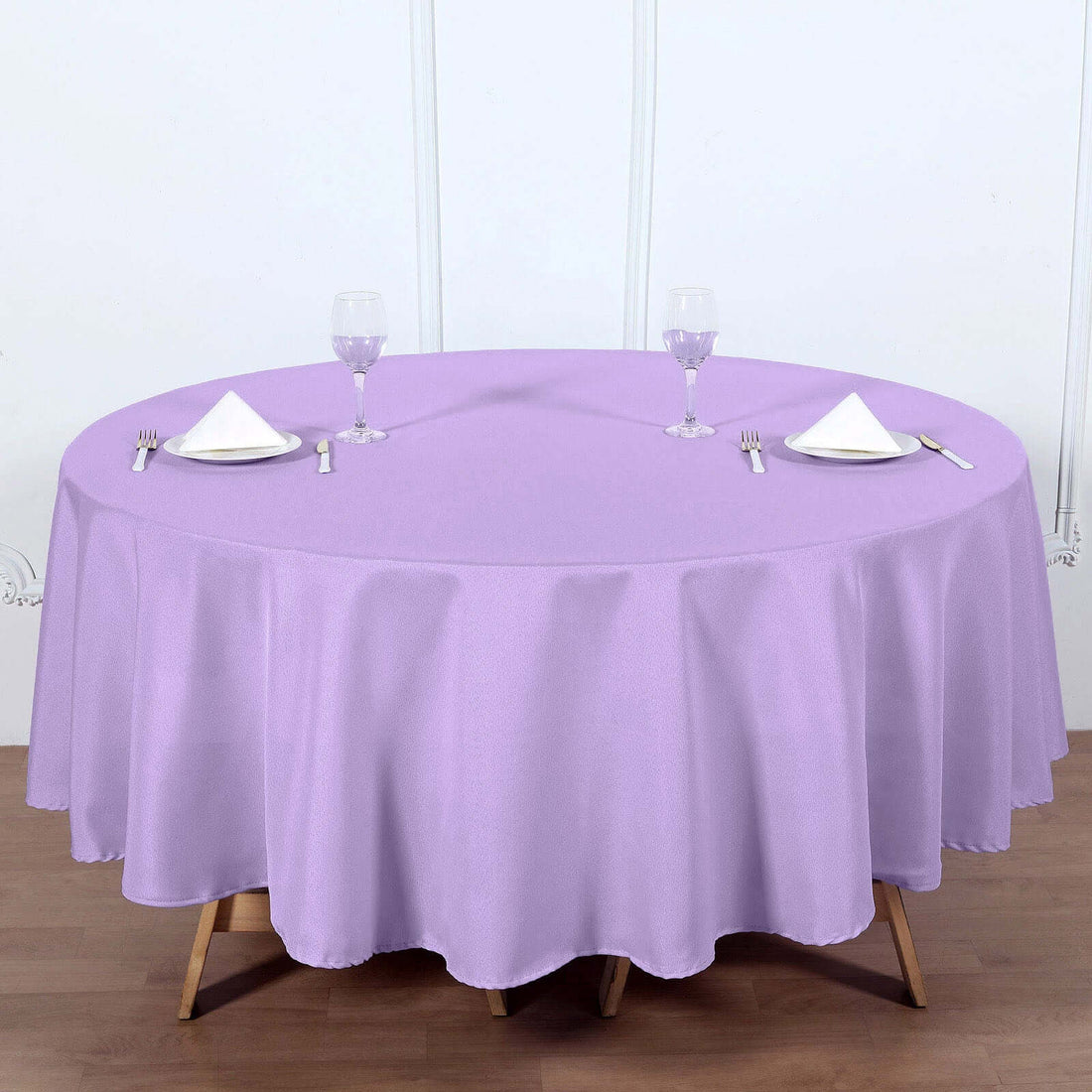 Purple round tablecloth on a dining table with utensils and glasses