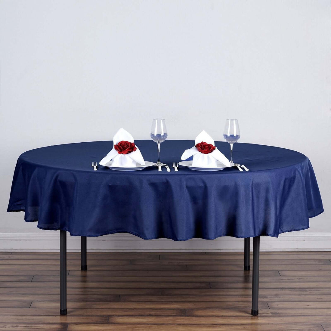 Navy tablecloth with elegant napkin folds and roses for dining setup.