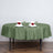 Round olive green tablecloth set for dining with elegant napkin and rose decor.