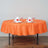 Orange round tablecloth on a dining table with elegant napkin and glass setup.