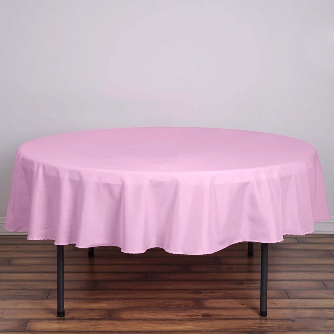 Round pink tablecloth on a wooden table.