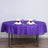 Purple tablecloth draped over a round table set for dinner with decorative napkins.