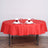Red round tablecloth with elegant napkin and rose centerpiece on a dining table.
