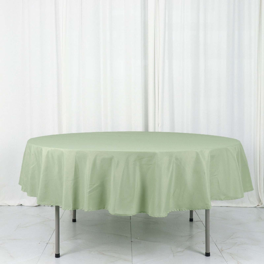 Round green tablecloth on a table against a white backdrop.