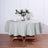 Round gray tablecloth draped over a wooden table with floral centerpiece.