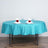 Turquoise tablecloth with elegant red rose napkins on a round table setting.