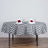 Round table set with black and white checkered tablecloth, decorated with flowers and glasses.