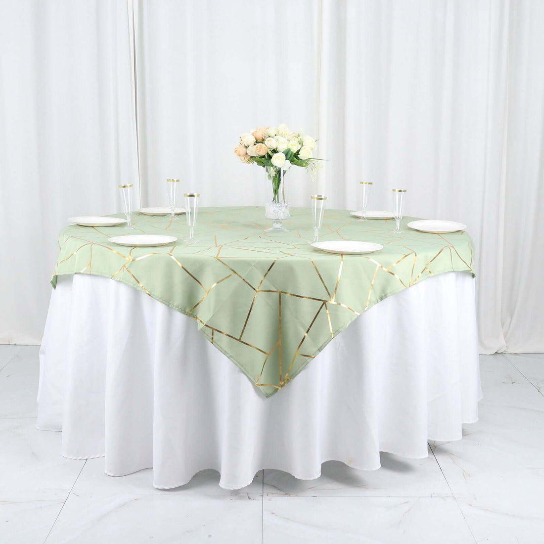 Round table set with sage green geometric tablecloth and floral centerpiece