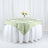 Round table set with sage green geometric tablecloth and floral centerpiece