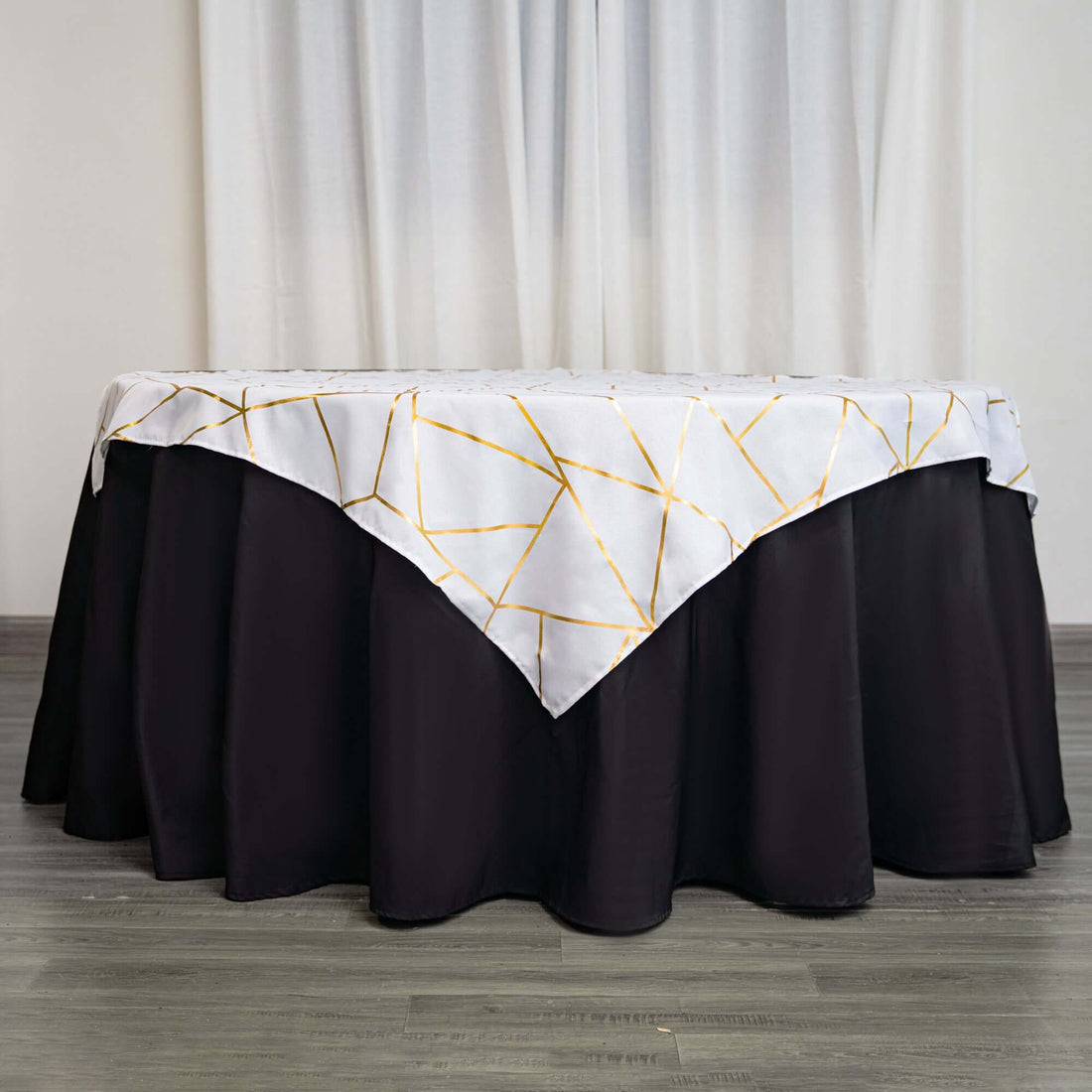 Table with gold geometric patterned tablecloth on a black skirt.