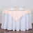 Peach tablecloth draped over a round table set with glasses and napkins.