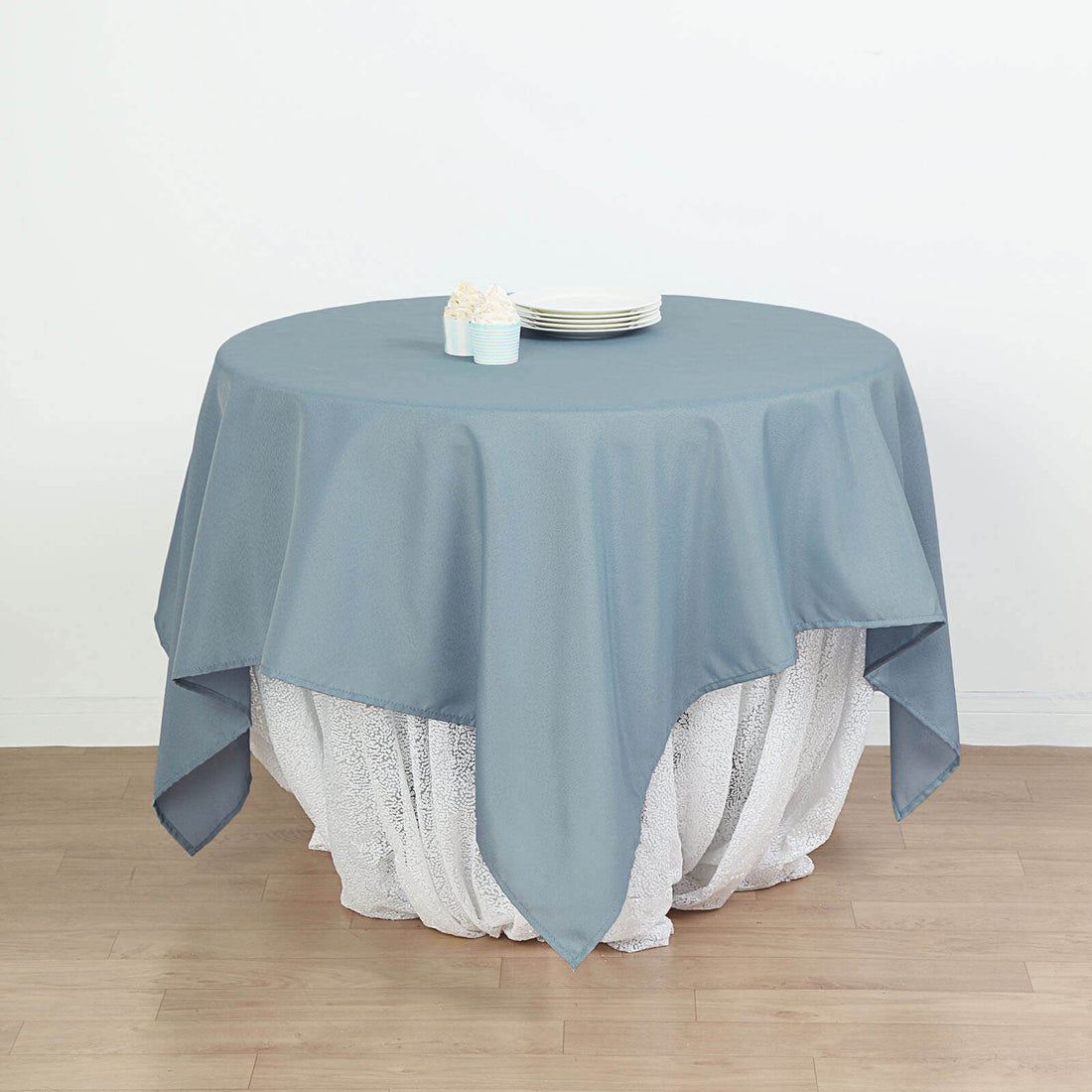 Round blue tablecloth draped elegantly over a white lace table.