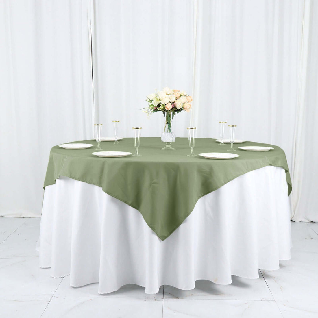Round table set with a green tablecloth and floral centerpiece.