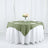 Round table set with a green tablecloth and floral centerpiece.